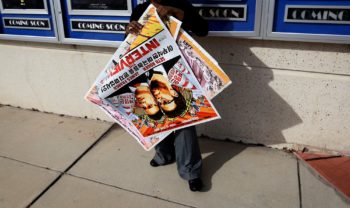 A poster for the movie "The Interview" is carried away by a worker after being pulled from a display case at a Carmike Cinemas movie theater, Wednesday, Dec. 17, 2014, in Atlanta. Georgia-based Carmike Cinemas has decided to cancel its planned showings of "The Interview" in the wake of threats against theatergoers by the Sony hackers. (AP Photo/David Goldman)