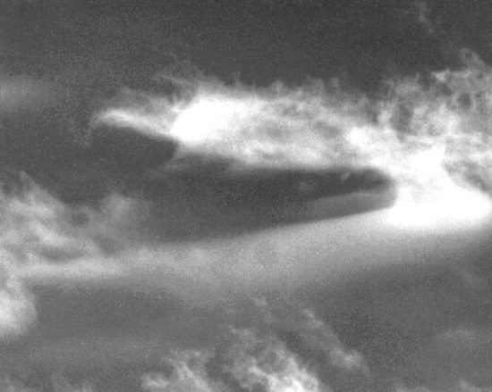 Black and White photo cropped and enlarged of two UFO's The larger is a triangular shaped craft and the smaller is a bell shaped craft. Note the sun's reflection on the upper portion of the bell shaped craft and on the upper portion of the triangular craft. 
