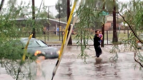 Tucson police officer carries a small child away from flooding. (Twitter Photo/@Tucson_Police)